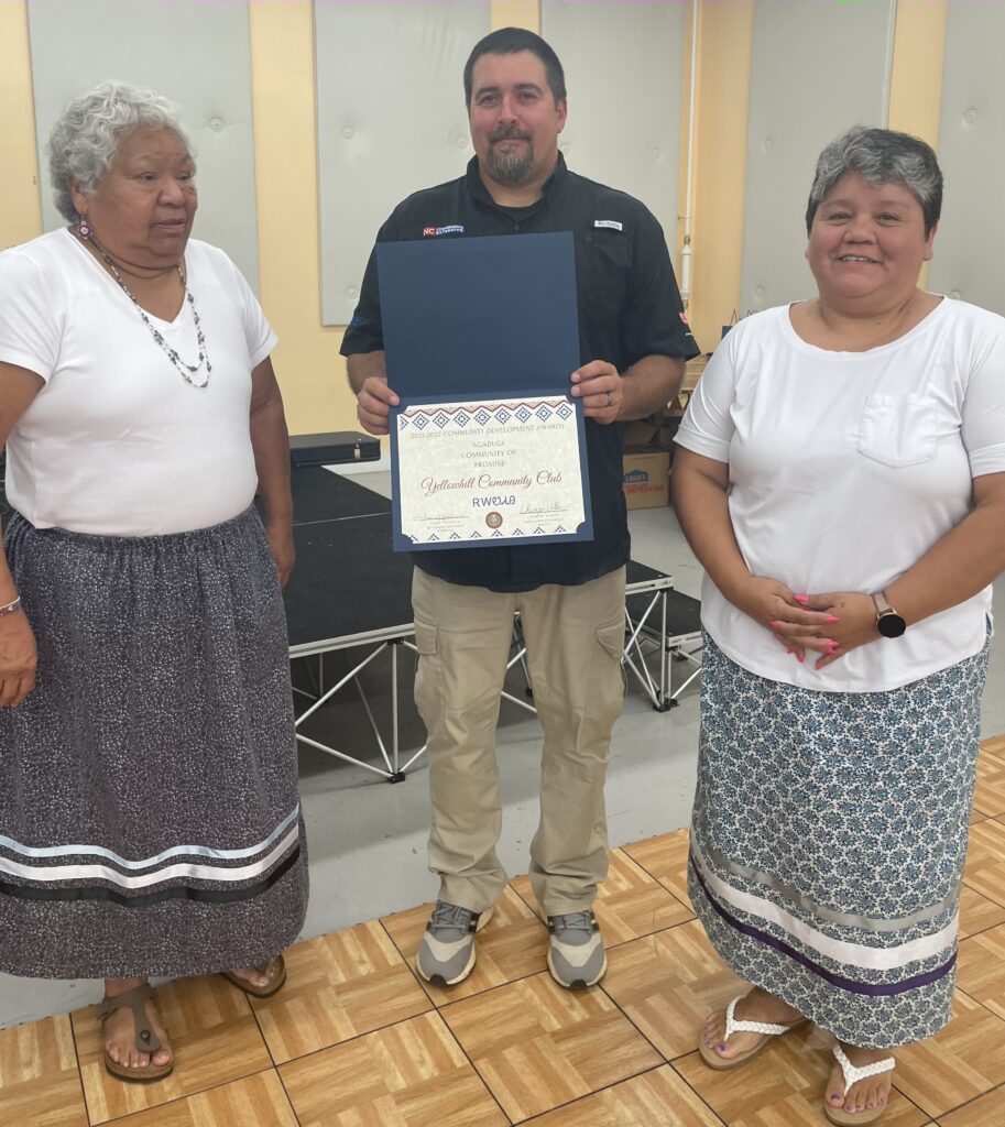  A man presents a certificate to two women.