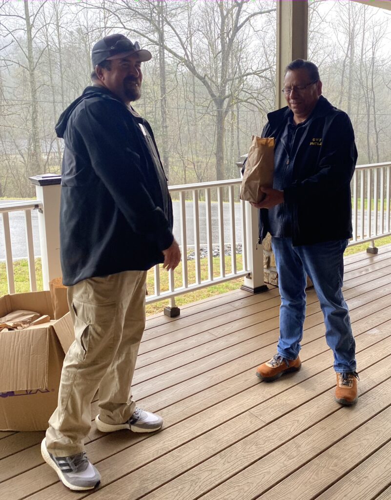 Two men stand on a porch.